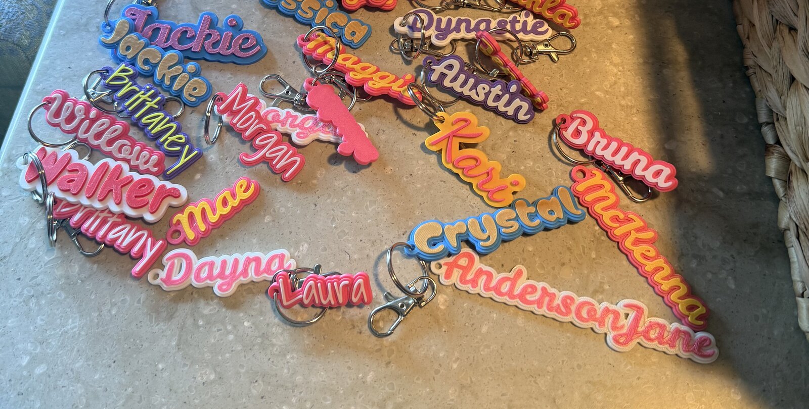 A wide view of many colorful, personalized 3D-printed name keychains