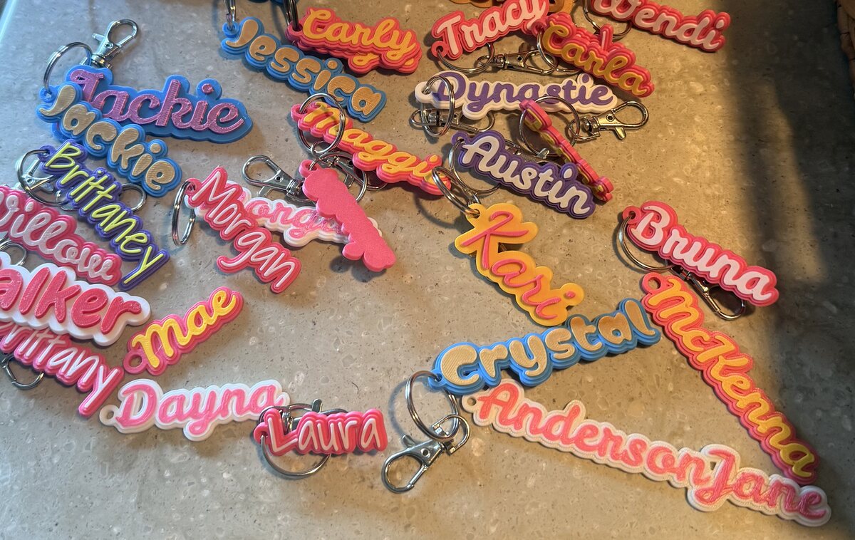 A centered view of many colorful, personalized 3D-printed name keychains
